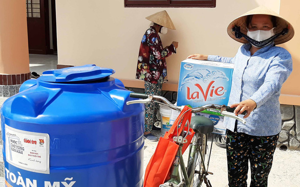 Người dân huyện Châu Thành, tỉnh Bến Tre nhận bồn nước cùng quà tặng từ bạn đọc hỗ trợ - Ảnh: CHÍ HẠNH